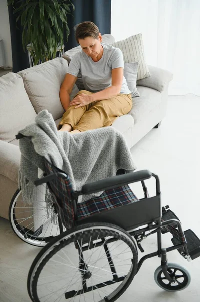 老妇人想从沙发上坐上轮椅 — 图库照片