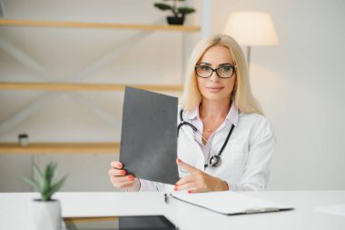 Klinikte doktor üniforması giyen orta yaşlı kadın..
