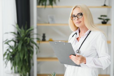 Orta yaşlı kadın doktor reçete yazıyor..