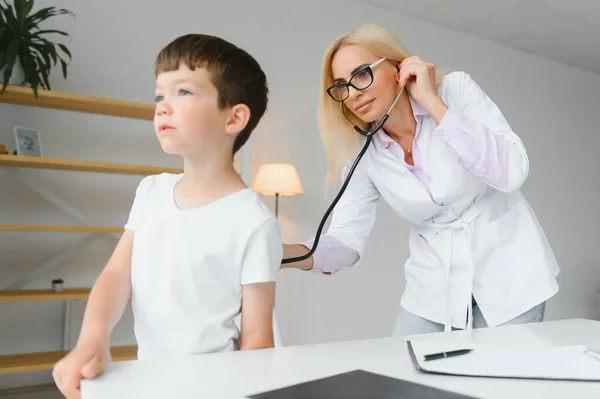 Doctor pediatrician examines child. Female doctor puts a stethoscope to a child's chest and listens to the little boy's heartbeat and lungs. Concept of health care and pediatric medical examination