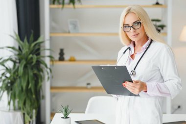 Klinikte doktor üniforması giyen orta yaşlı kadın..