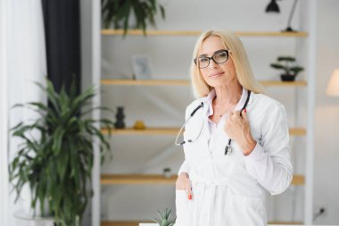 Laboratuvar önlüğü ve steteskop giyen kadın doktor hastanede dikilirken elinde pano tutuyormuş.