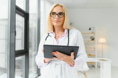 Klinikte doktor üniforması giyen orta yaşlı kadın..