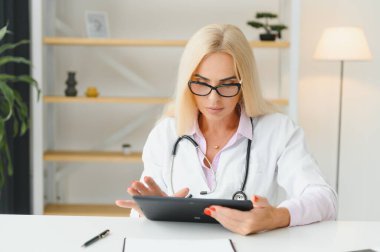 Orta yaşlı kadın doktor reçete yazıyor..