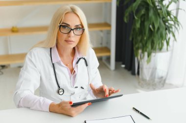 Klinikte doktor üniforması giyen orta yaşlı kadın..