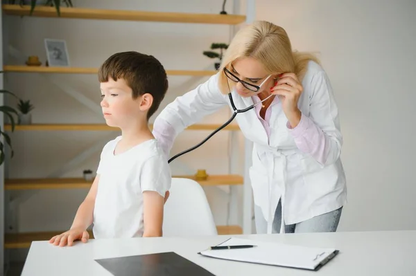 Doctor pediatrician examines child. Female doctor puts a stethoscope to a child\'s chest and listens to the little boy\'s heartbeat and lungs. Concept of health care and pediatric medical examination