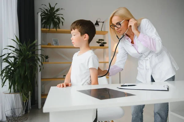 Doctor pediatrician examines child. Female doctor puts a stethoscope to a child\'s chest and listens to the little boy\'s heartbeat and lungs. Concept of health care and pediatric medical examination