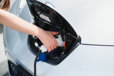 Eko elektrikli araba konsepti. Elektrikli arabanın şarj olmasını bekleyen kadın.