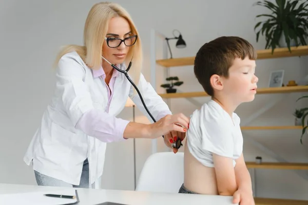 Doctor pediatrician examines child. Female doctor puts a stethoscope to a child\'s chest and listens to the little boy\'s heartbeat and lungs. Concept of health care and pediatric medical examination