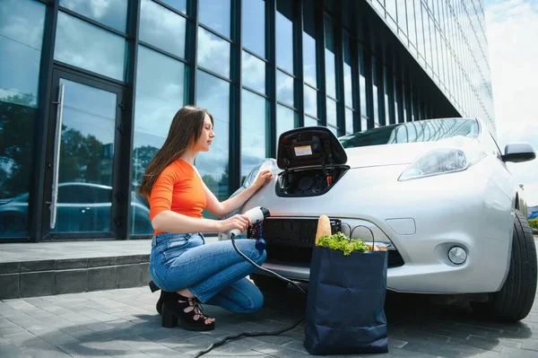 Şarj oluyor. Gündüz vakti elektro-mobil arabasıyla gezen genç bir kadın..