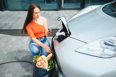 Şarj oluyor. Gündüz vakti elektro-mobil arabasıyla gezen genç bir kadın..