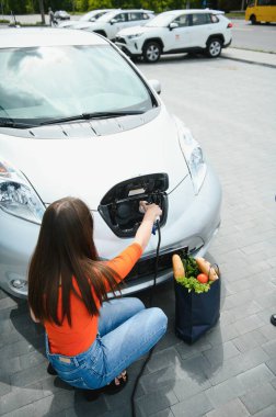 Eko elektrikli araba konsepti. Elektrikli arabanın şarj olmasını bekleyen kadın.