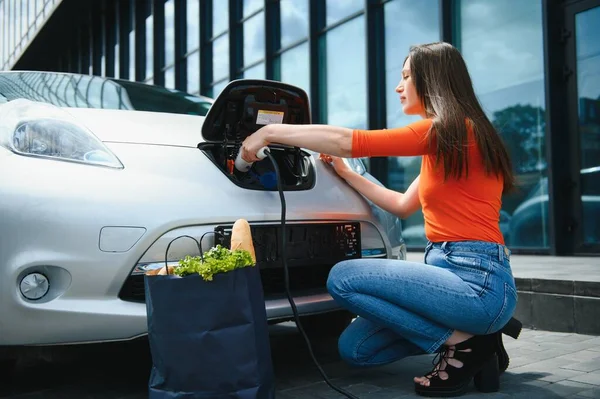 Woman charging electro car at the electric gas station.