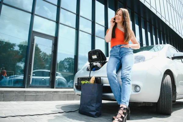 電気ガソリンスタンドで電気自動車を充電する女 — ストック写真