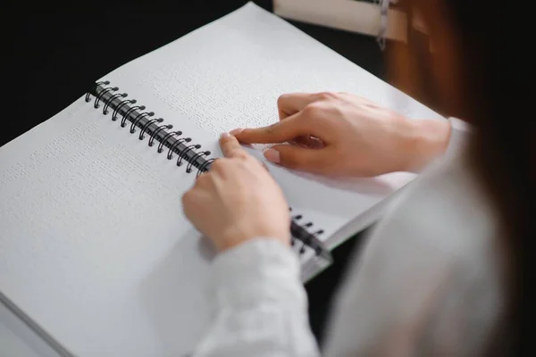 Blind woman read book written in Braille.