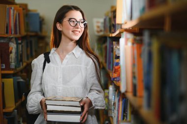 Kütüphanede. Lise kütüphanesinde kitapları olan güzel bir kız öğrenci.