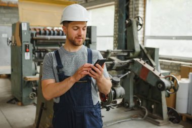 Yönetim ekibi, mühendis ya da ustabaşı. Fabrikadaki endüstriyel üretim yönetimi ile ilgili iş bilgilerini telefonla kontrol ediyoruz. Takım çalışması konsepti.