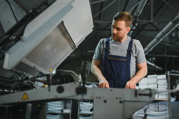 worker in protective clothing in factory using machine.