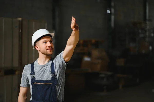 Smiling and happy employee. Industrial worker indoors in factory. Young technician with white hard hat