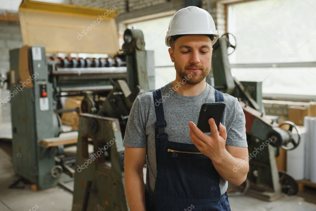 Management team, engineer, or foreman. Standing checking job information about industrial production management within the factory by phone. Teamwork concept.