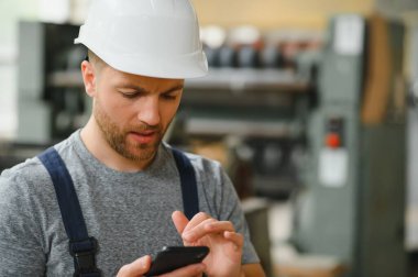 Yönetim ekibi, mühendis ya da ustabaşı. Fabrikadaki endüstriyel üretim yönetimi ile ilgili iş bilgilerini telefonla kontrol ediyoruz. Takım çalışması konsepti.