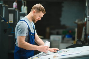Baskı fabrikasının çalışma masasında spektrometreyle yazıcı rengini ölçen bir işçi..