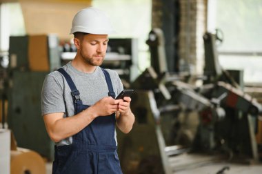 Yönetim ekibi, mühendis ya da ustabaşı. Fabrikadaki endüstriyel üretim yönetimi ile ilgili iş bilgilerini telefonla kontrol ediyoruz. Takım çalışması konsepti.