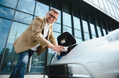 Elektrikli otomobil için güç konektörü tutan adam.