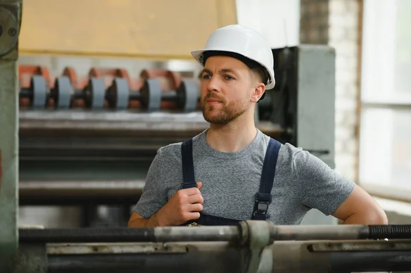 worker in protective clothing in factory using machine.