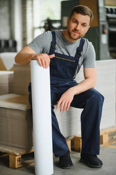 Baskı fabrikasındaki modern ambalaj makinesinin üretim sürecini kontrol eden işçilerin portresi.
