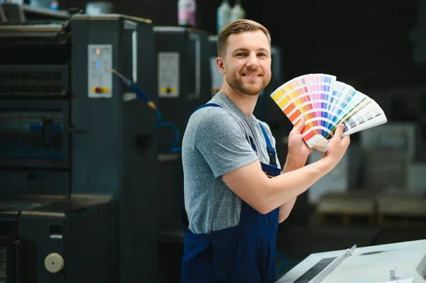 Man working in printing house with paper and paints.