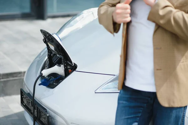 Man charges an electric car at the charging station.