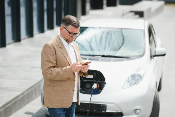 Ein Geschäftsmann Lädt Ein Elektroauto — Stockfoto