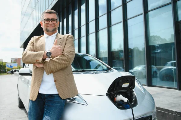 Man charges an electric car at the charging station.