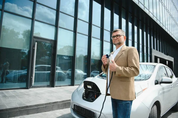 Adam Şarj Istasyonunda Bir Elektrikli Arabayı Şarj Ediyor — Stok fotoğraf