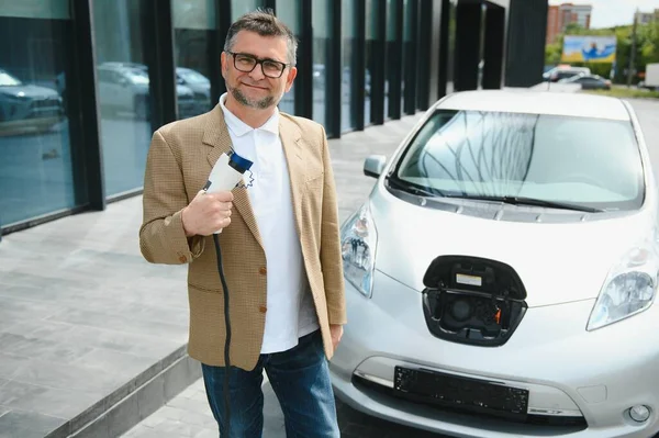 Man charges an electric car at the charging station.