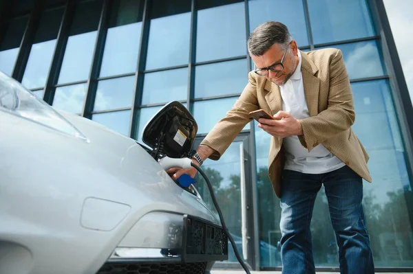 Mann Hält Stromanschluss Für Elektroauto — Stockfoto