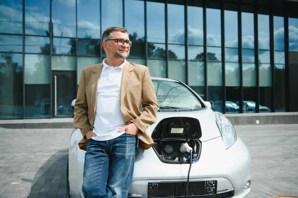 Man charges an electric car at the charging station.