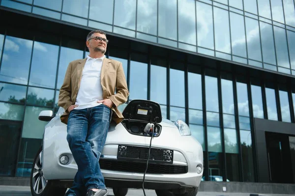 Man charges an electric car at the charging station.