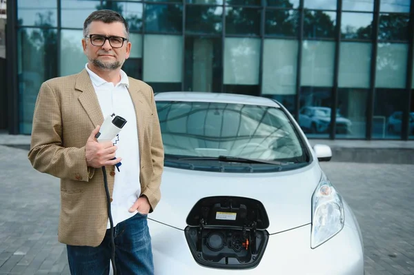 Man charges an electric car at the charging station.