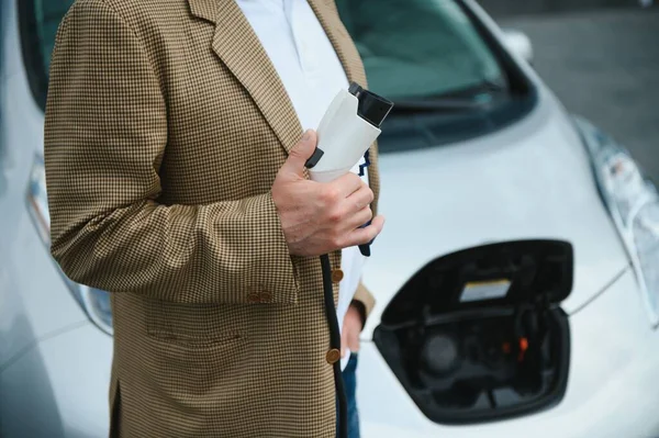 Man charges an electric car at the charging station.