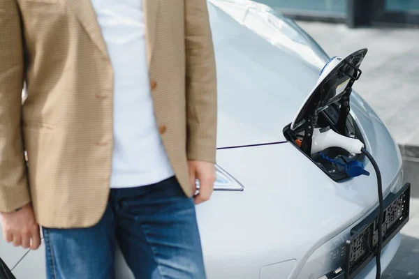 Man charges an electric car at the charging station.