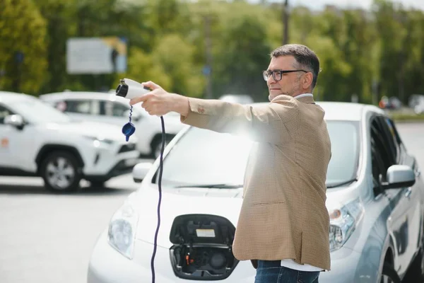 Man charges an electric car at the charging station.