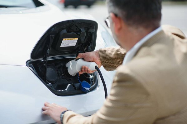 Man holding power connector for electric car.