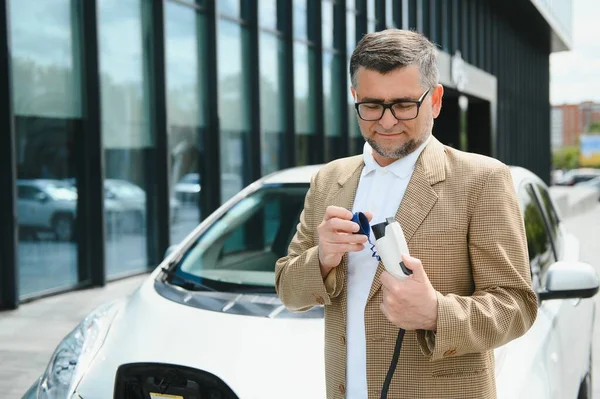 Mann Hält Stromanschluss Für Elektroauto — Stockfoto