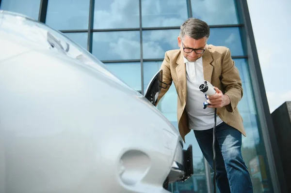 Schöner Mann Mit Ladekabel Einer Stromtankstelle Die Neben Seinem Neuen — Stockfoto