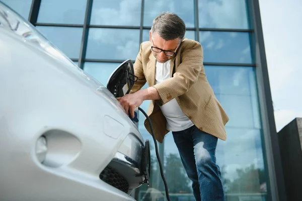 Ein Geschäftsmann Lädt Ein Elektroauto — Stockfoto