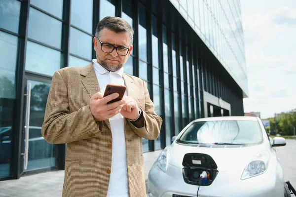 Schöner Mann Benutzt Handy Während Das Auto Geladen Wird — Stockfoto