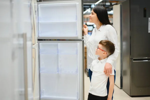 family uying domestic refrigerator in supermarket.