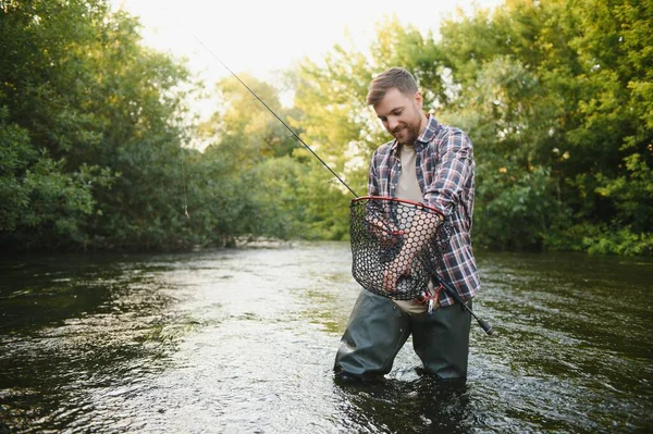男人拿着钓竿 渔夫在外面的河水里钓鱼 用网捕鳟鱼 暑期钓鱼业余爱好 — 图库照片